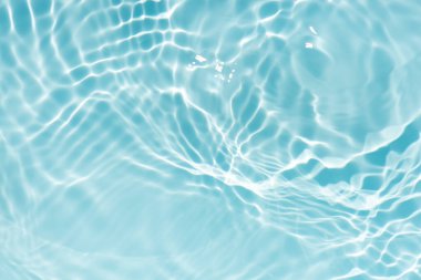 Yüzeydeki mavi su dalgaları bulanıklaştı. Defocus bulanık mavi şeffaf, berrak, durgun su yüzeyi dokusu sıçrama ve kabarcıklarla bulanıklaştırılmış. Parlak desenli arka planda su dalgaları.