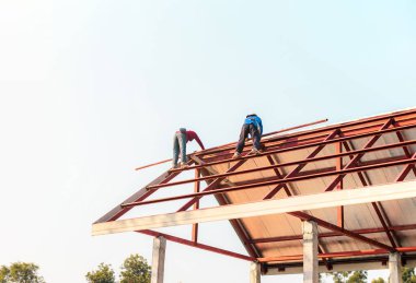 Özel koruma işinde çalışan çatıcı eldiven giyer, hava veya pnömatik çivi tabancası kullanır, yeni çatının tepesine asfalt kiremit yerleştirir, inşaat halindeki konut kavramı.