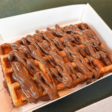 Mukavva tabakta çikolata kaplı zengin bir waffle. Masanın üzerinde.
