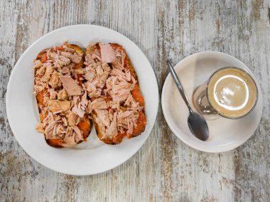 Tipik bir lezzetli kahvaltı, bir bardak sütlü kahve ve rendelenmiş domates ve ton balığından oluşan iki dilim tost..