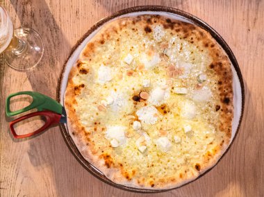 Yeni yapılmış 4 peynirli pizza. Au gratin ve çeşitli peynirlerden oluşur: mozzarella, beyaz çedar, kırmızı çedar ve mavi peynir. Büyük bir tabakta servis edilir.. 