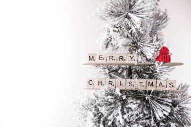 Tahta harflerle Noel mesajı olan yapay Noel ağacı. Soldaki boşluğu kopyala. Tebrik kartı için ideal