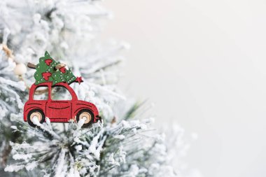 Noel ağacında üstünde ağaç olan bir araba. Süslü karla süslenmiş yapay plastik bir ağaca yerleştirilmiş kırmızı tahta bir figür. Boşluğu Sağda Kopyala