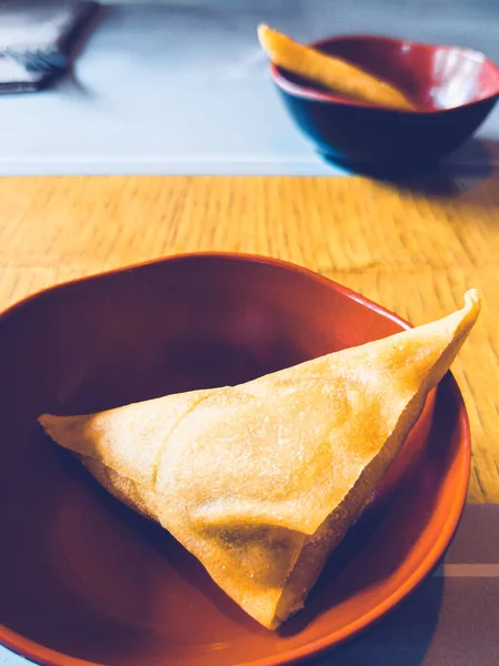 Bir Çin lokantasında servis edilen sebzeli samosa ile bir kasenin dikey görüntüsü. Arka planda, odakta değil, başka bir samosa ile başka bir kase. Aperatif olarak sunuldu..