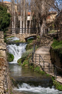 Taştan binalar ve yeşilliklerle çevrili eski bir köyden çağlayan şelalenin manzarası. Barışçıl ve resimli Avrupa kırsal manzarası.