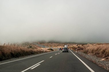 Viraja yakın bir kamyonu geçiyor. Yoğun bir sis yükseliyor. Yol üzerinde, ters yönde, bir dönüş oku çizilmiş ve sağ tarafı gösteren iki yönlü bir at arabasının eksenine yerleştirilmiş.