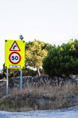 50 km / saat hız limitinin aşılamayacağı tehlikeli bir virajda sarı dikey işaret.