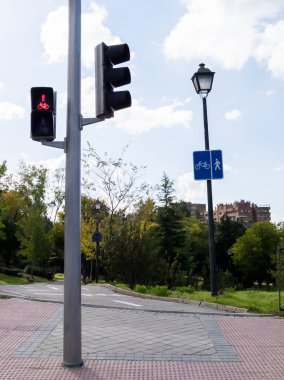 Madrid sokaklarından birinde, şu anda onlar için kırmızı olan ve araçlara yol veren bisiklet ve yayaların geçişini düzenleyen bir trafik ışığı bulmadık. Caddenin karşı tarafında dikey bir tabela var.