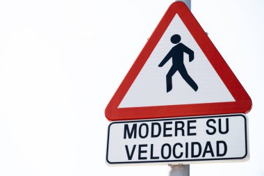 Kırmızı kenarları ve beyaz arkaplanı olan bir üçgenin dikey işareti. Yürüyen bir yayanın figürü. Sürücülerin orta hız kullanmaları gerektiğini, çünkü yolda yayalar olabileceğini gösteriyor. İşaretin altında da bir işaret var.