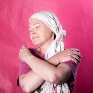 Göğüs kanseri olduğu için onkolojik tedavi gören bir kadının kare görüntüsü. Sevgiyle kendine sarılıyor, çünkü güç dışında, hastalıktan muzaffer olarak çıkmak zorunda olduğu bir duygu.. 