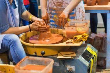 Seramik bir zanaat gösterisinde ıslak kil şekillendirmekle uğraşan zanaatkarların elleri