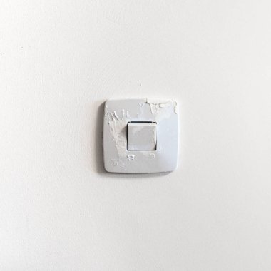 Bir ressam koyu renkli bir duvar boyadı, eskiden yaptığı ve temizlemeyi unuttuğu eski ışık düğmesini boyadı. Boya kurudu ve nesne artık çıkarılamaz. Kare resim