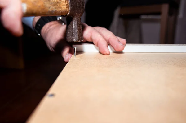 Evde tek başına iş yapan bir adamın ellerini görebilirdiniz. Tam o anda adam eline bir çekiç alır ve çiviyle tahtaya vurmaya hazırlanır..