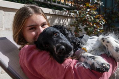 Ergen, köpeği hamakta uzanmış sabah güneşinin tadını çıkarırken kameraya bakıyor..