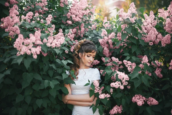 Shy brunette looking down in pink lilac flowers — Stock Photo, Image