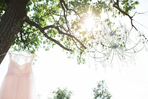 Brudklänning och ljuskronan hänger på kedjan utomhus — Stockfoto