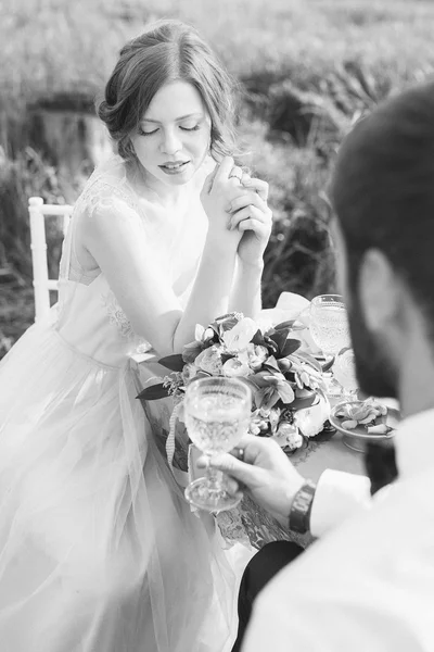 Mooie bruid neerkijkt zittend aan tafel met toekomstige echtgenoot — Stockfoto