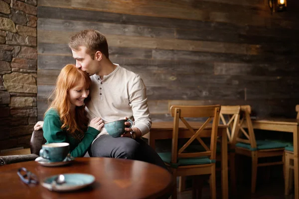 Man med kaffe kyssa hans leende flickvän i huvud — Stockfoto