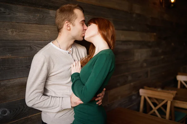 Paar küsst sich in Café gegen Holzwand — Stockfoto