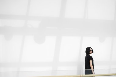 Karşı güneş gözlüğü ile gölge güneşli duvar siyah saçlı kadın