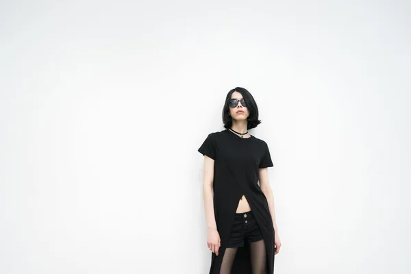 Portret van een jonge vrouw in zwarte poseren tegen van witte muur — Stockfoto