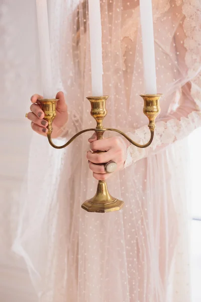 Noiva segurando candelabros dourados — Fotografia de Stock