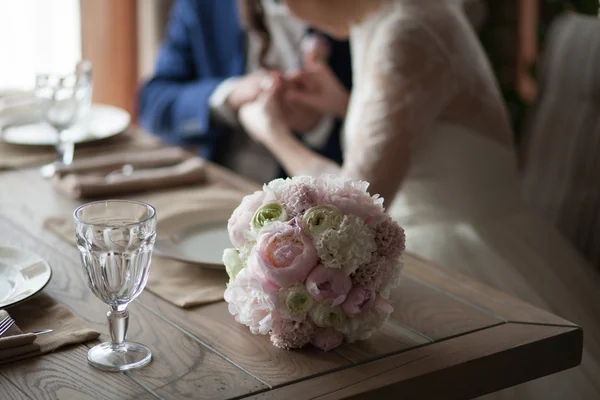 Όμορφη ανθοδέσμη στο τραπέζι ενάντια νέα των συζύγων — Φωτογραφία Αρχείου