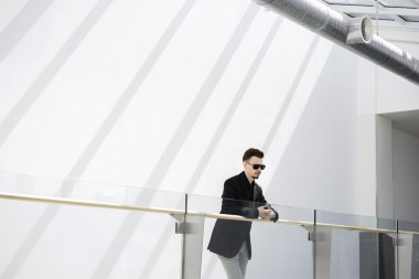 Küpeşte eğilerek güneş gözlüklü genç adam