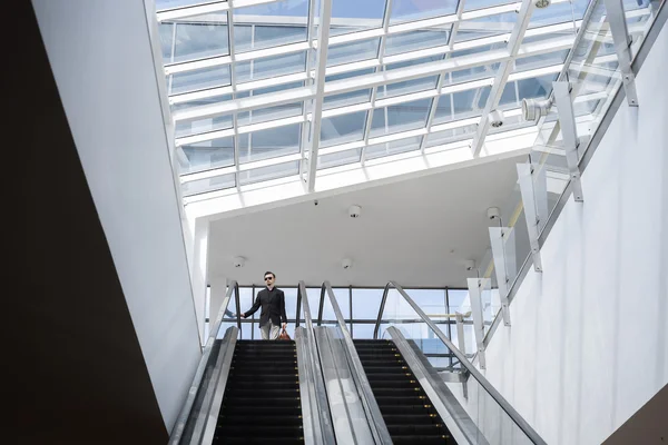 Mannen på rulltrappan i modern byggnad Royaltyfria Stockbilder