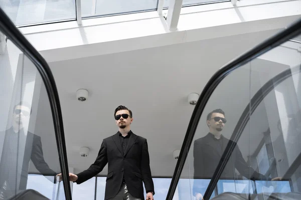 Mann mit Sonnenbrille auf Treppe im Sonnenlicht Stockbild