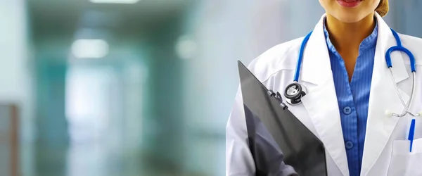 Woman doctor holding patient records on blurry out patient department of hospital, conception of modern medical with technology and data conection for early diagnosis. Front Liner while standing