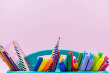 Ofis malzemeleri, yazı ve çizim araçları, ofis, ev, okula dönüş için masa düzenleyicileri, kalemler, keçeli kalemler, fosforlu kalemler, fosforlu kalemler, pembe üzerine izole edilmiş renkli kalemler..