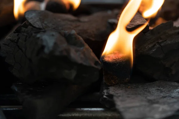 Barbekü kömür çakmağında parlayan mangal kömürü kömürleri. Alevler, mangal kömürünün içine konan yangın başlatıcılarını kullanmaya başladı..