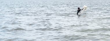 Balıkçı gün içinde balık yakalamak için sahile ağ atıyor.