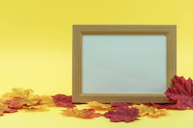 Sarı arka planda, sonbahar yapraklı boş ahşap çerçeve. Düz yatıyordu. Uzayı kopyala Üst görünüm