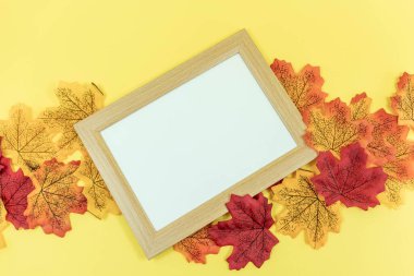 Sarı arka planda, sonbahar yapraklı boş ahşap çerçeve. Düz yatıyordu. Uzayı kopyala Üst görünüm