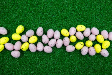 Renkli Sarı ve Pembe Paskalya yumurtası otların üzerinde çil desenleri ve fotokopi alanı