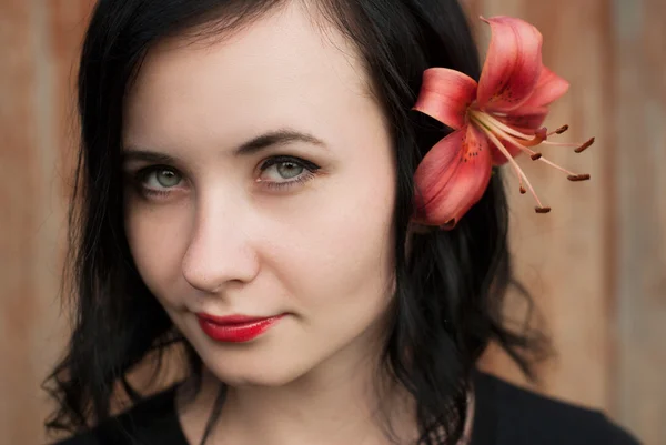 Beautiful girl with flower in her hair, a brunette in a black shirt posing,