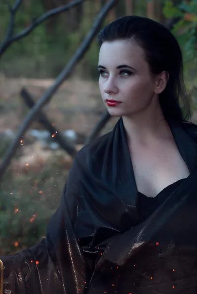 Una joven bruja en el bosque, una mujer con un vestido oscuro sobre un fondo de viejas ramas , —  Fotos de Stock