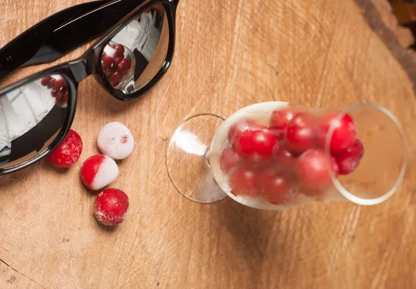 Cerezas congeladas en los vasos y gafas de sol en una mesa de madera — Foto de Stock