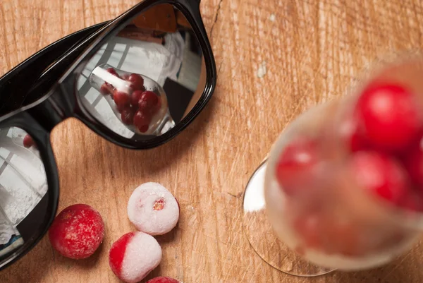 Заморожені вишні в окулярах і сонцезахисних окулярах на дерев'яному столі — стокове фото