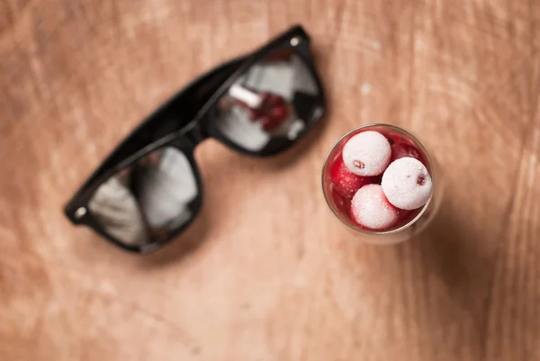 Cerezas congeladas en los vasos y gafas de sol en una mesa de madera —  Fotos de Stock