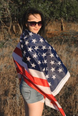 Kız açık havada Amerikan bayrağı ile yıldızlar ve çizgiler flutters Rüzgardaki bayrak,