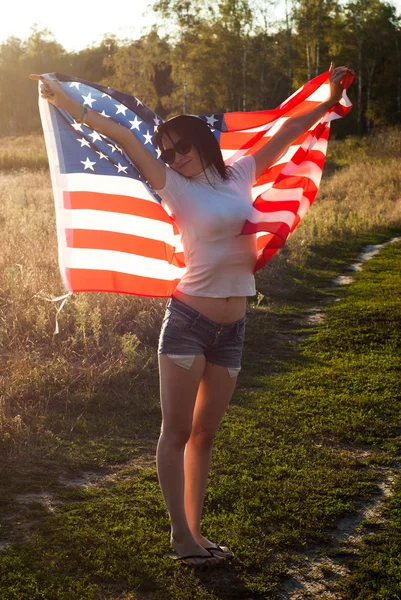 屋外にアメリカ国旗を持つ少女、星とストライプ旗風になびき, — ストック写真