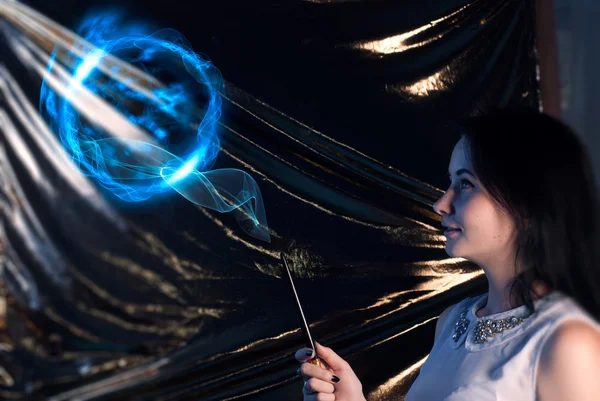 Girl with magic wand brunette-the sorcerer's apprentice, on a gold background, uses the spell — Stock Photo, Image