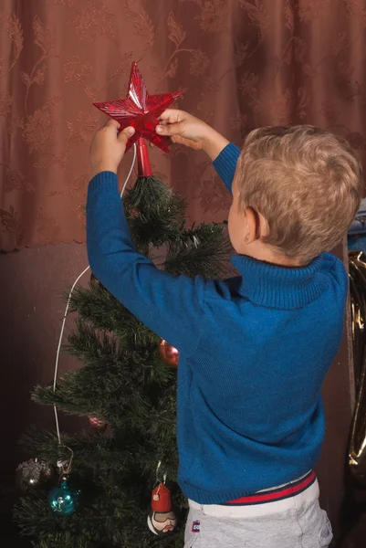 the boy is 5 years old dresses up Christmas tree, preparing for the holidays,