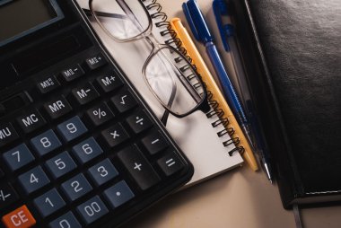 Hesap makinesi, gözlükleri ve bir Not Defteri tablosundaki, deri notebook,