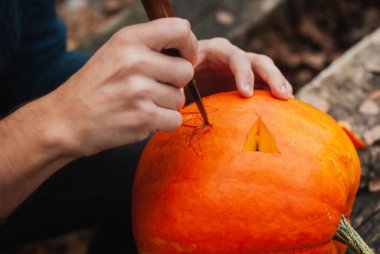 Adam balkabağından Jack o fenerini oyuyor. Yakından.,