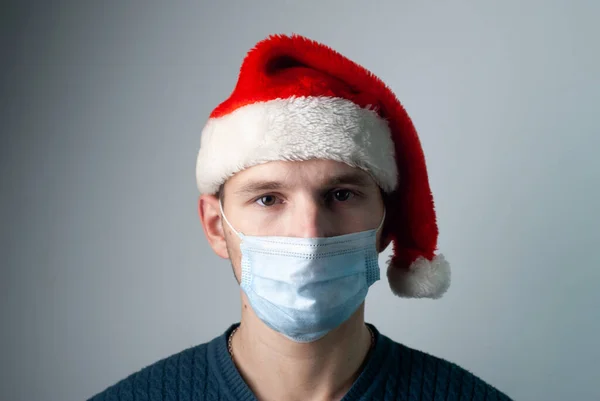 Szomorú fiatalember orvosi maszkban, világjárvány koncepció karácsonyra — Stock Fotó