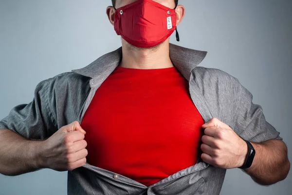 Super hombre con máscara médica roja rasga camisa en el pecho Imagen De Stock